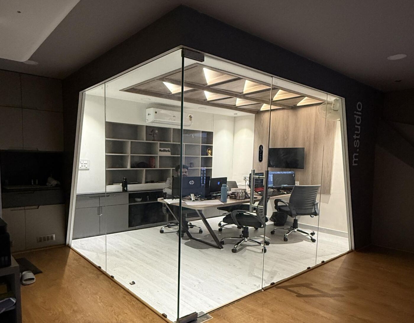 Modarch Studio office — a glass-walled workspace with a sculptural wooden ceiling